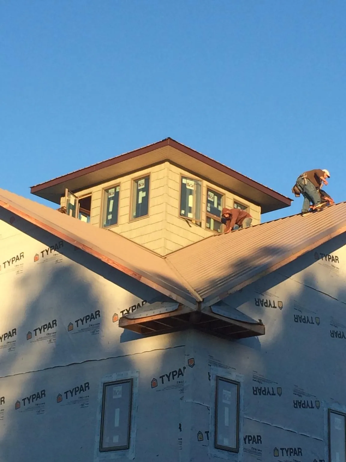 Roofers working around a rooftop cupola on a new metal roof at sunset — Roof Waterproofing in Watertown by Roofing Brothers